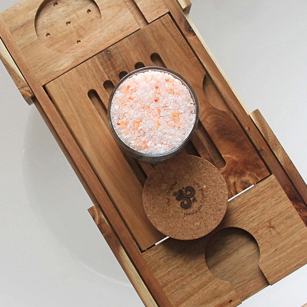 Relax Bath Salts product glass jar filled with Himalayan Crystal Salt, cork cover  resting on wooden tray with slats and candle holder groove resting on white tub